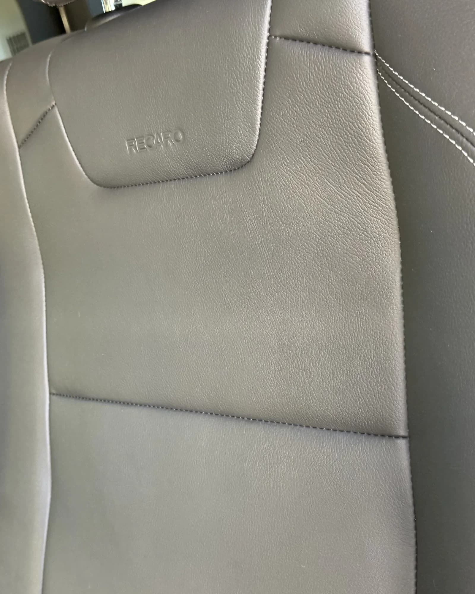 Clean vehicle seat upholstery with visible stitching after interior detailing.